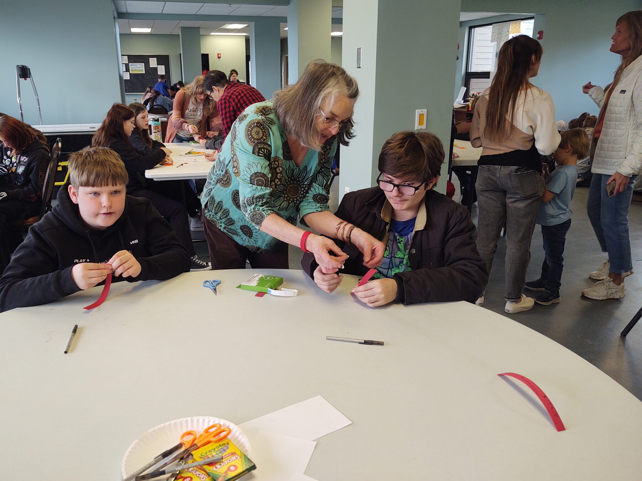 Local artist and educator, Nanette Seligman, assists a student with his bracelet to demonstrate the Purkinje effect.
